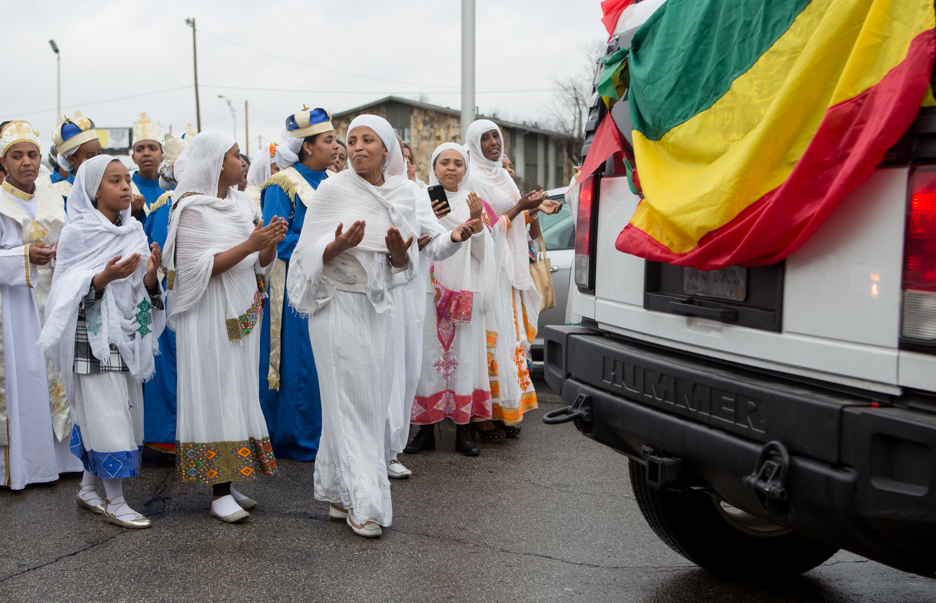 women walking behind a car during a Timket celebration