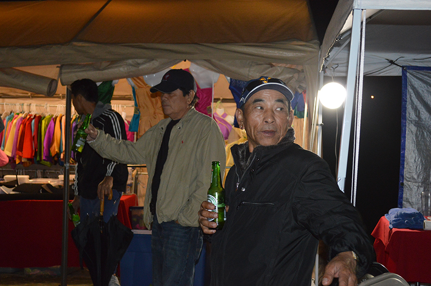 3 men drinking beer in a vendor tent